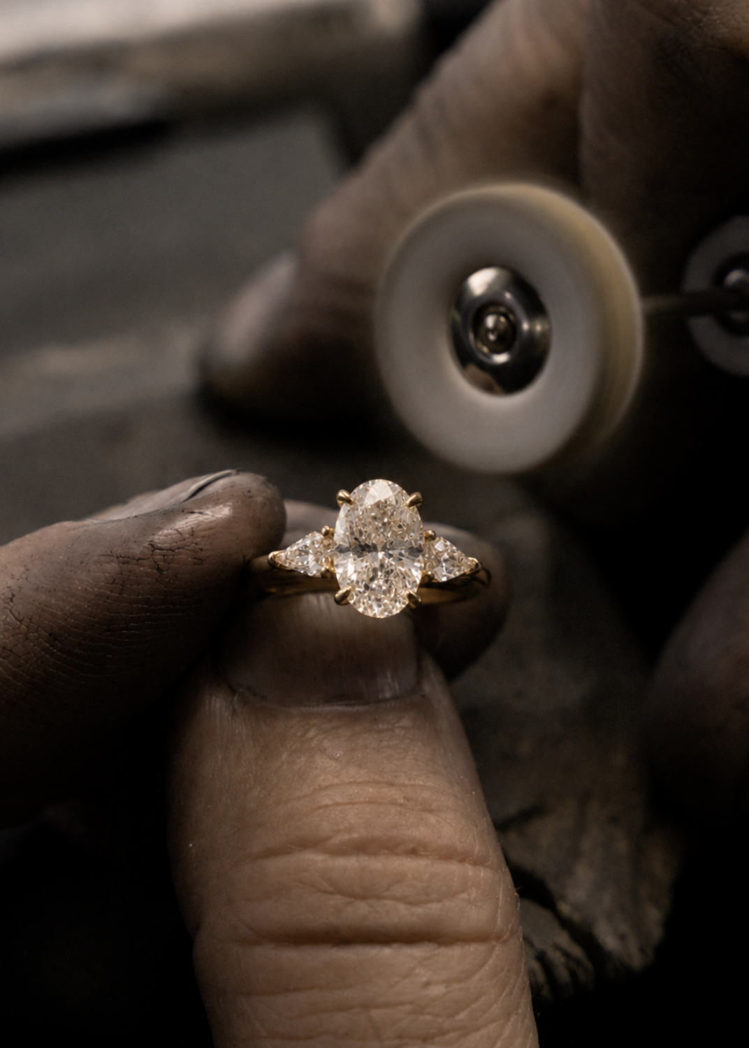 Diamond ring held between fingers with a magnifying glass in the background